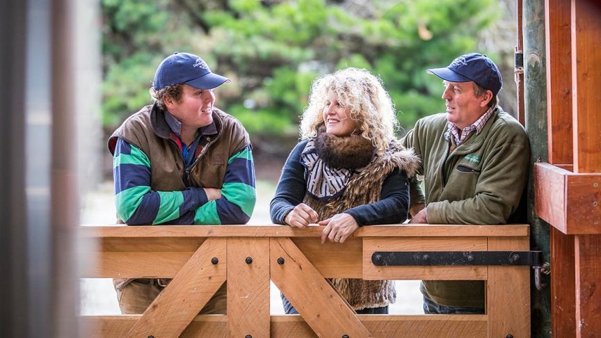 three people standing at fence 