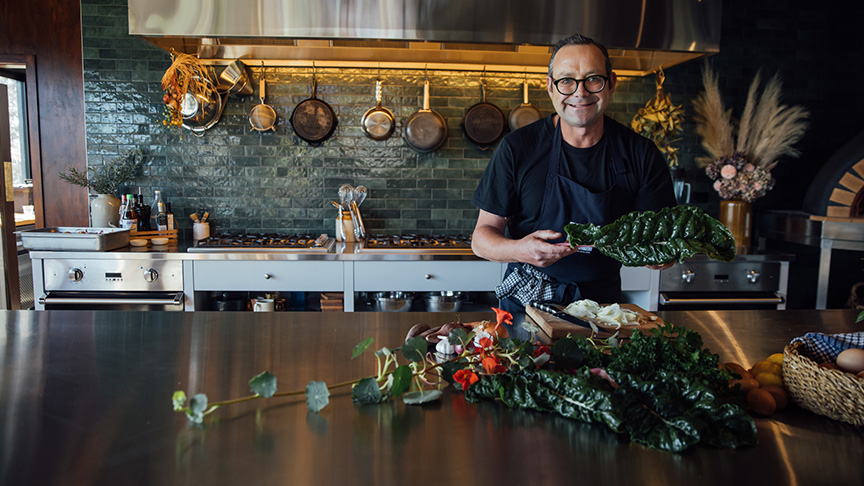 Michael Van de Elzen holding silverbeet standing at kitchen counter