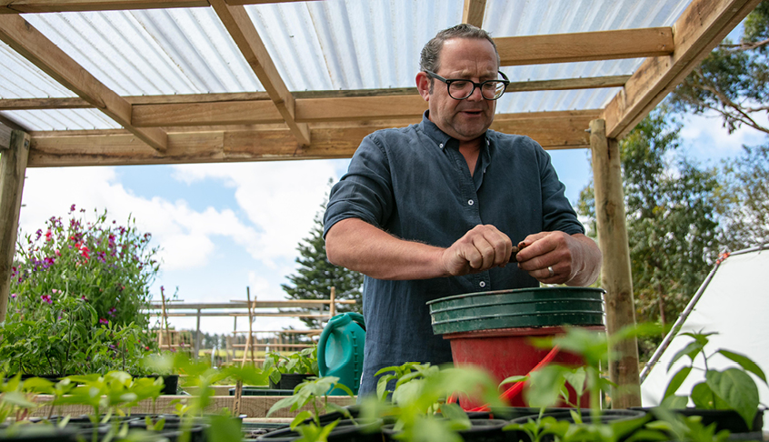 Michael Van de Elzen planting seeds in a raised garden bed 