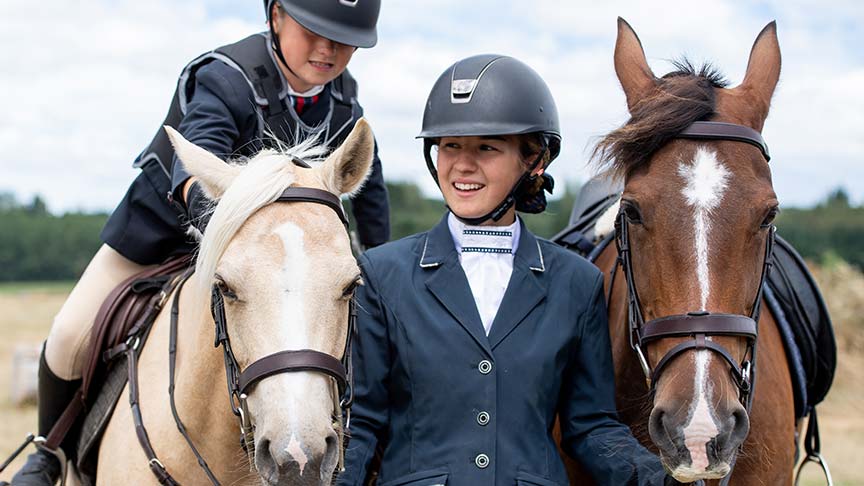 young woman standing between two horses 