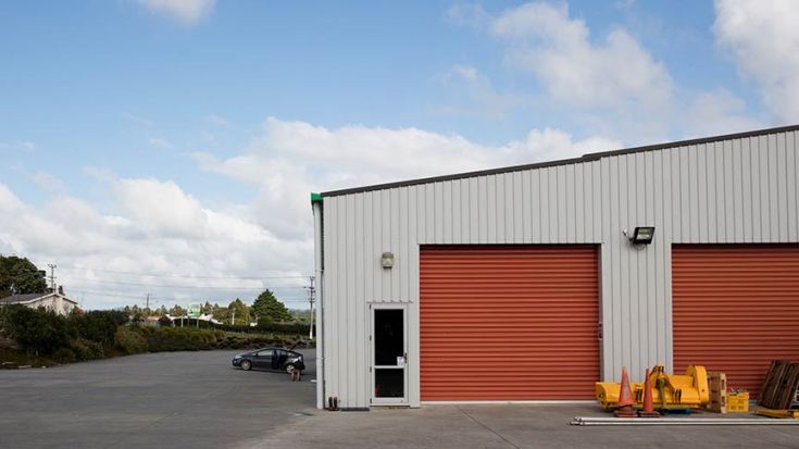white commercial storage building with two orange vehicle doors 
