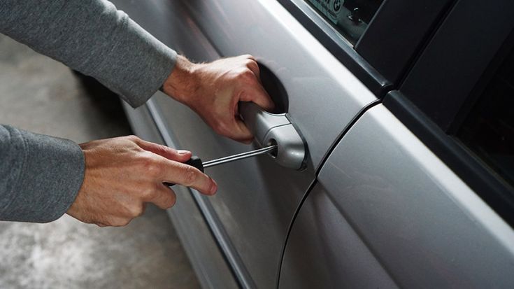 person breaking into car with screwdriver