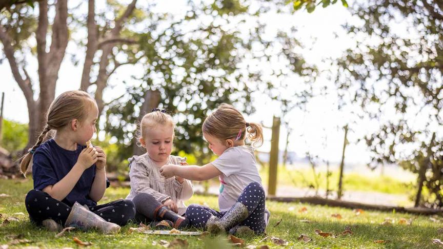 three young children playing in grass 