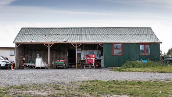 Green farm shed with quad bike and other implements visible