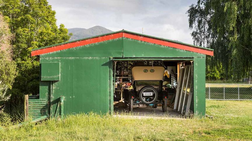 Green shed with vintage car parked inside 
