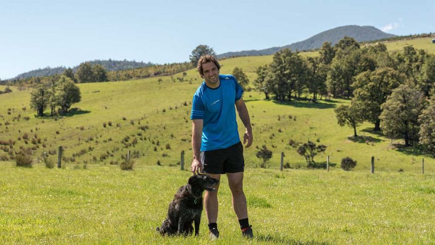 Sam Whitelock bending down petting dog 