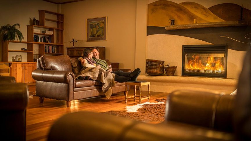 Couple sitting on couch in front of fireplace 