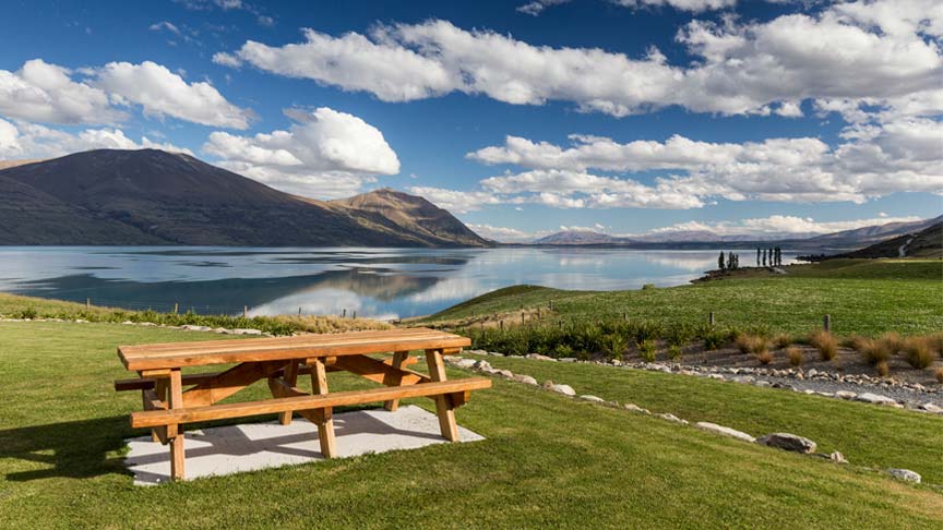 picnic table on hillside with lake in background 