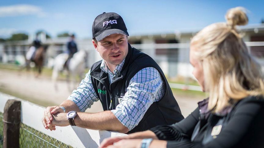 Two FMG advisers leaning against fence talking 