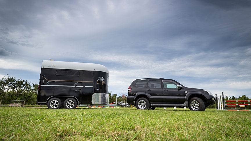 black SUV pulling horsefloat