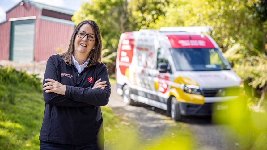 Gill Rolfe standing with her arms crossed in front of Melanoma NZ branded car