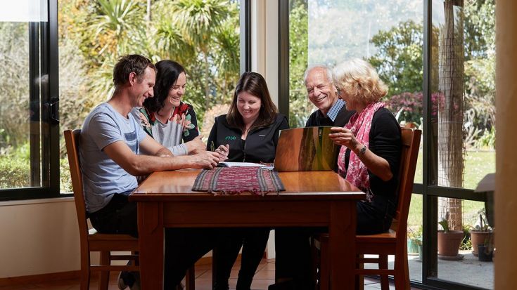 four people sitting at table with FMG adviser talking to one another 