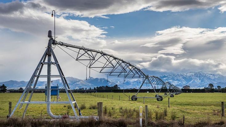 Irrigator stretching out over paddock with mountains in background 