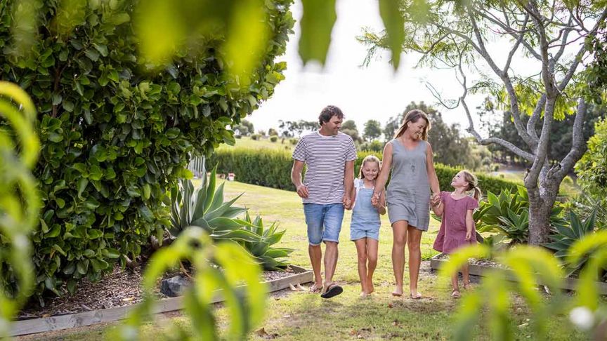 couple walking hand in hand with two young daughters in garden 