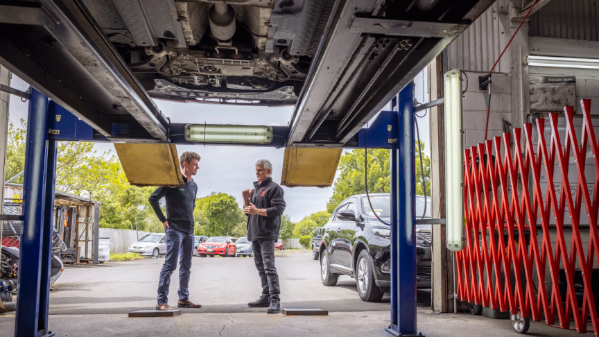 Two men talking in a mechanics garage 